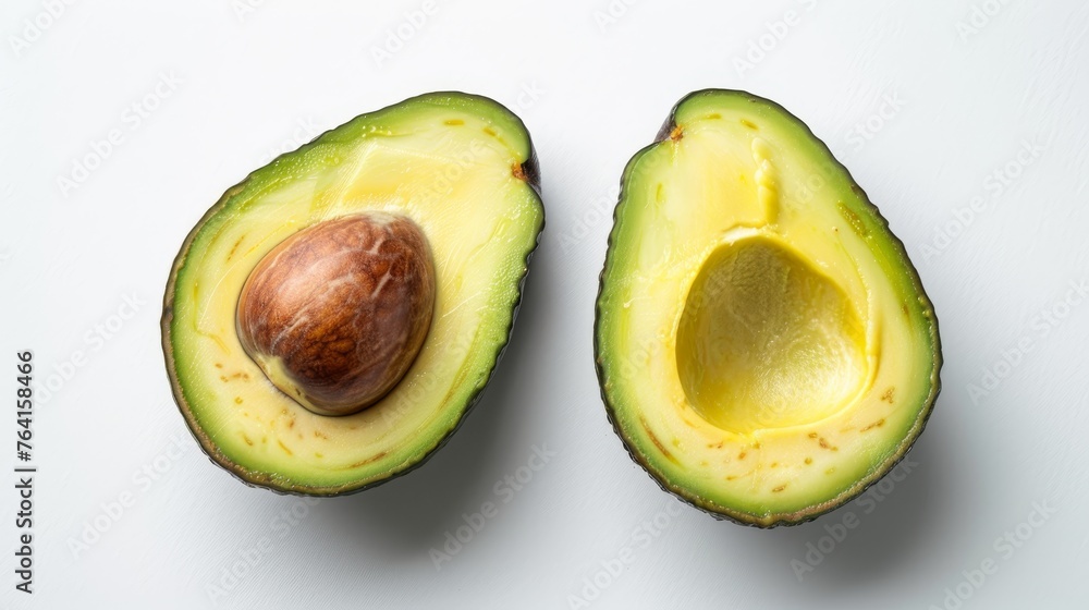 An open avocado with one half containing the pit and the other hollow, on a clean white surface.