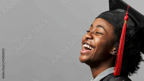 The unbridled joy of a graduate is captured as she laughs wholeheartedly, her academic cap aloft, celebrating her triumph. photo