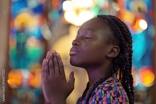 A young girl of African ethnicity praying inside church blured background. Christian religious prayer and devotion photo