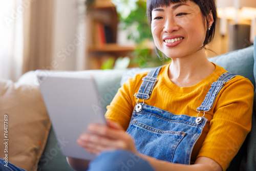 Woman using tablet computer while relaxing at home