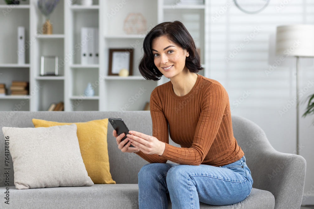 Smiling woman using smartphone on cozy living room couch Smiling woman using smartphone on cozy living room couch