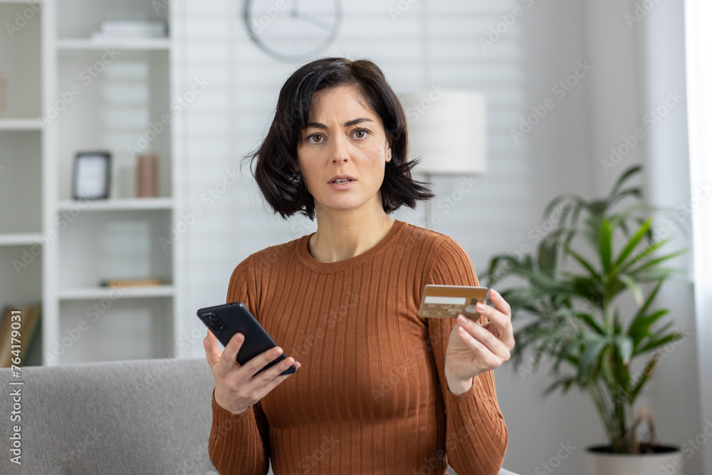 Concerned woman holding credit card and smartphone Concerned woman holding credit card and smartphone