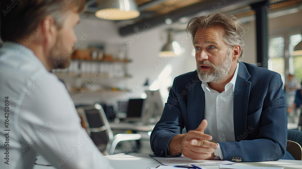 Two professional men in conversation at a modern office setting. Two professional men in conversation at a modern office setting.