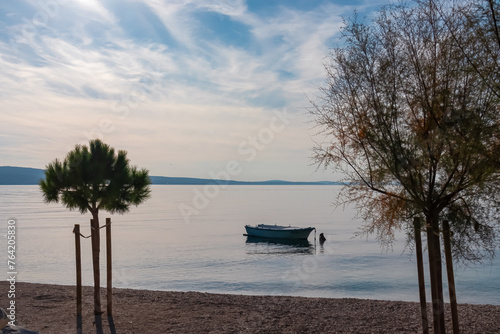 Fototapeta Naklejka Na Ścianę i Meble -  Scenic view of small fishing boat on idyllic sand beach Plaza Brzet in coastal town Omis, Split-Dalmatia, Croatia, Europe. Adriatic Mediterranean Sea in summer at sunset on Balkans. Vacation concept
