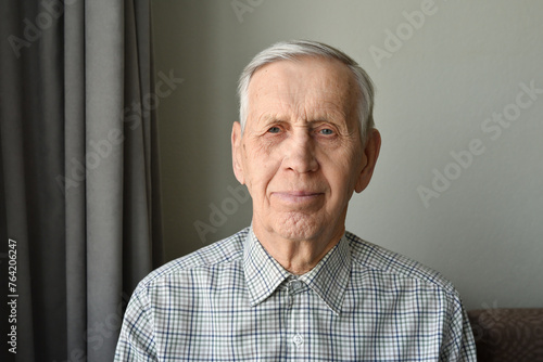 Portrait of an old man, content and happy, 85 years of age. The elderly man is wearing a shirt and is looking into the camera with a smile on his face. photo