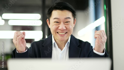 Wallpaper Mural Happy excited asian businessman received great news on laptop sitting at workplace in business office. Shocked surprised smiling man in formal suit reads a positive good message on computer. Close up Torontodigital.ca