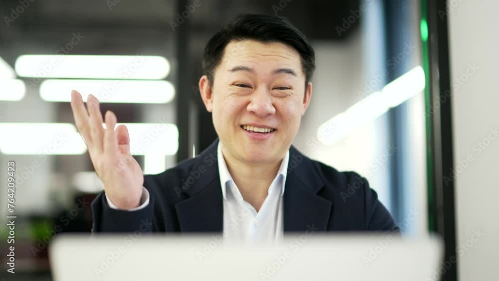 Satisfied happy asian businessman received great news on laptop while sitting at workplace in business office. Smiling glad mature man in formal suit reads positive good message on computer. Close up Satisfied happy asian businessman received great news on laptop while sitting at workplace in business office. Smiling glad mature man in formal suit reads positive good message on computer. Close up