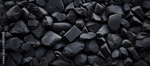 A close-up view of a heap of black rocks against a dark background photo