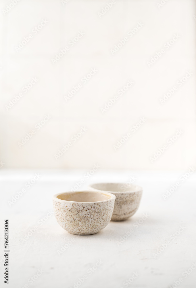 two ceramic tea bowls. Ceramic saucepan for handmade sauce. Minimalism style. Front view. Japanese ceramics. Tea ceremony. Close-up.