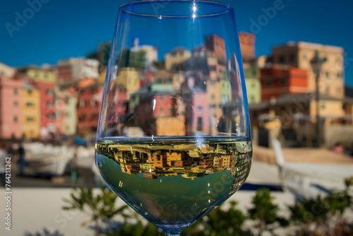 A glass of Vermentino Wine in front of Boccadasse, the pitoresque fishermen village nearby Genoa.  photo