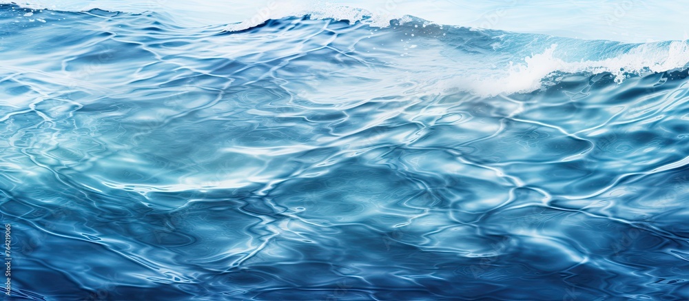 An up-close view of a gentle wave in the ocean against a backdrop of a bright blue sky An up-close view of a gentle wave in the ocean against a backdrop of a bright blue sky