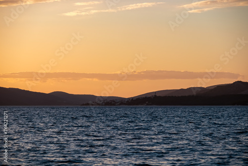 Fototapeta Naklejka Na Ścianę i Meble -  Romantic sunset in Okrug Gornij, Split-Dalmatia, Croatia. Coastline of island Otok Ciovo, Adriatic Sea in summer. Calm water surface of Mediterranean. Vacation vibes at the seaside. Tranquil serene