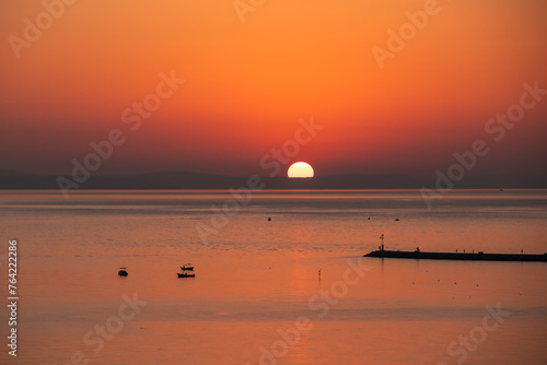 Sunset sail unfurls along the idyllic Omis Riviera, Adriatic Mediterranean Sea. Dramatic hues paint the sky as a romantic day dawns on Croatia tranquil South Dalmatian coast, Split-Dalmatia. Vacation