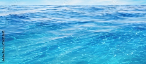 A serene blue ocean under a bright sun with gentle waves rippling on the surface