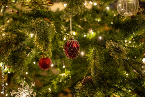 Low light Christmas decorations on Christmas tree creating a high end lifestyle look. Fairy lights and baubles.