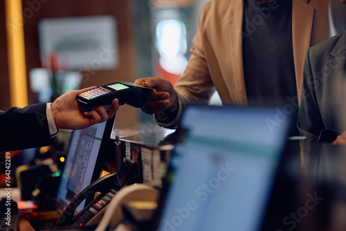 Fotografía Close up of African American man using credit card while paying at hotel reception desk