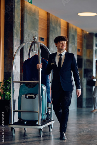 Fotografie Full length of happy bellhop at hotel lobby looking away.