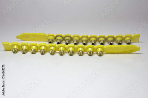powder actuated tool loads. spent and new cartridges, inserted into pair of yellow strips