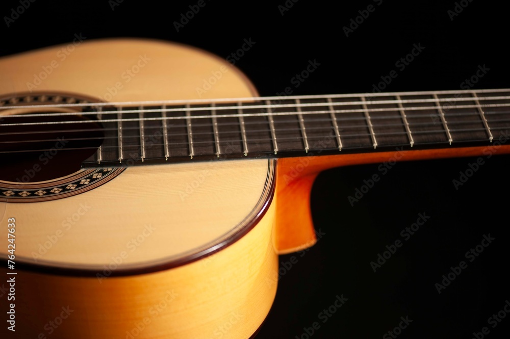 Classical Spanish flamenco guitar close up, dramatically lit isolated on black background with copy space.