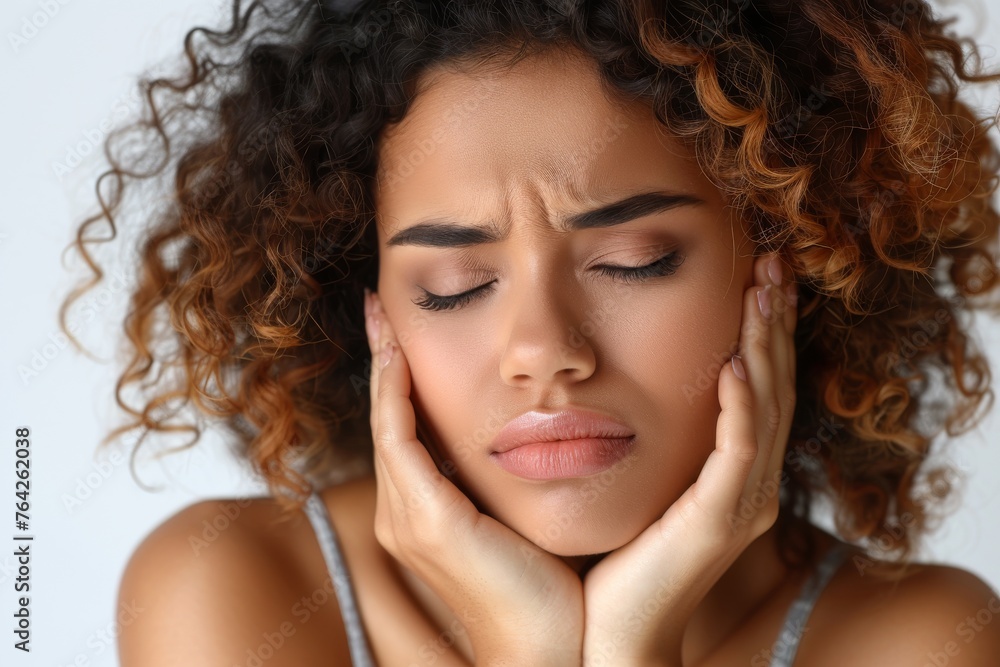 An expressive close-up of a female model with her eyes closed and hands on cheeks, suggestive of a toothache or facial pain An expressive close-up of a female model with her eyes closed and hands on cheeks, suggestive of a toothache or facial pain