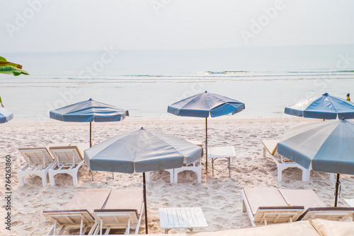 Rows of sun loungers and umbrellas on sandy beach in Tropical Beach vacation concept.