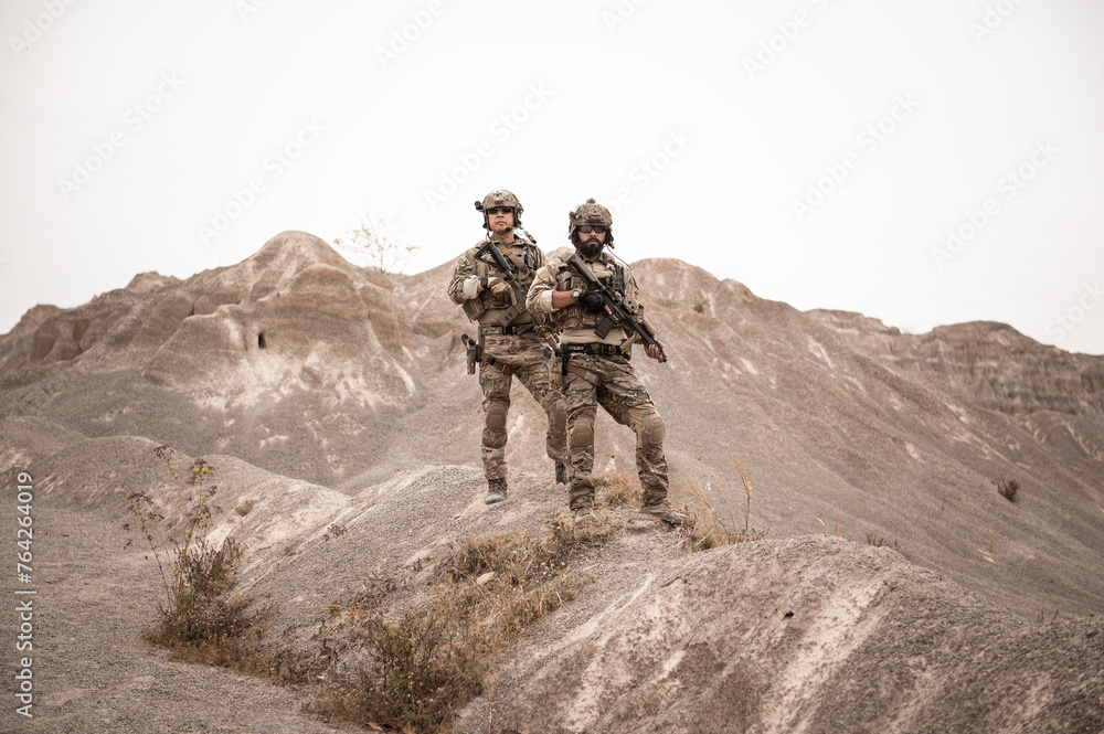 Soldiers in camouflage uniforms aiming with their rifles.ready to fire during military operation in the desert , soldiers training in a military operation Soldiers in camouflage uniforms aiming with their rifles.ready to fire during military operation in the desert , soldiers training in a military operation