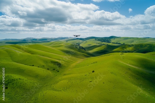A distant wide-angle shot capturing a plane flying over rolling green hills
