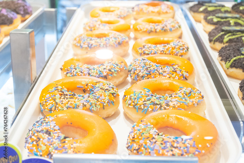 Display of delicious pastries in a bakery with assorted glazed donuts,Various donuts on shelf in Bakery, donuts in showcase of typical pastry shop in the street. photo