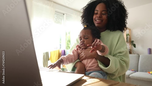 African American baby typing on his mother's laptop while working at home