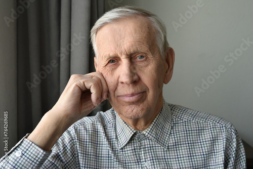 Close-up portrait of a handsome satisfied old man.  The elderly gentleman looks thoughtfully at the camera, smiling.