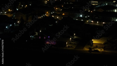 A night aerial view of a colorful condo unit next to a highway, revealing other buildings in the condominium complex. photo