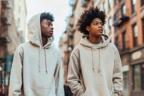 Two Afroamerican teenagers boys in blank hoodies walking in city street photo