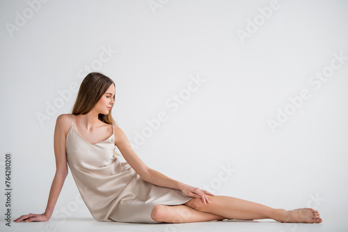 A woman is sitting on the floor in a white dress.