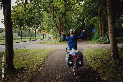 Junge passiert in Siegerpose mit seinem Rad das Ortsschild Münster während einer Radreise durch das Münsterland photo