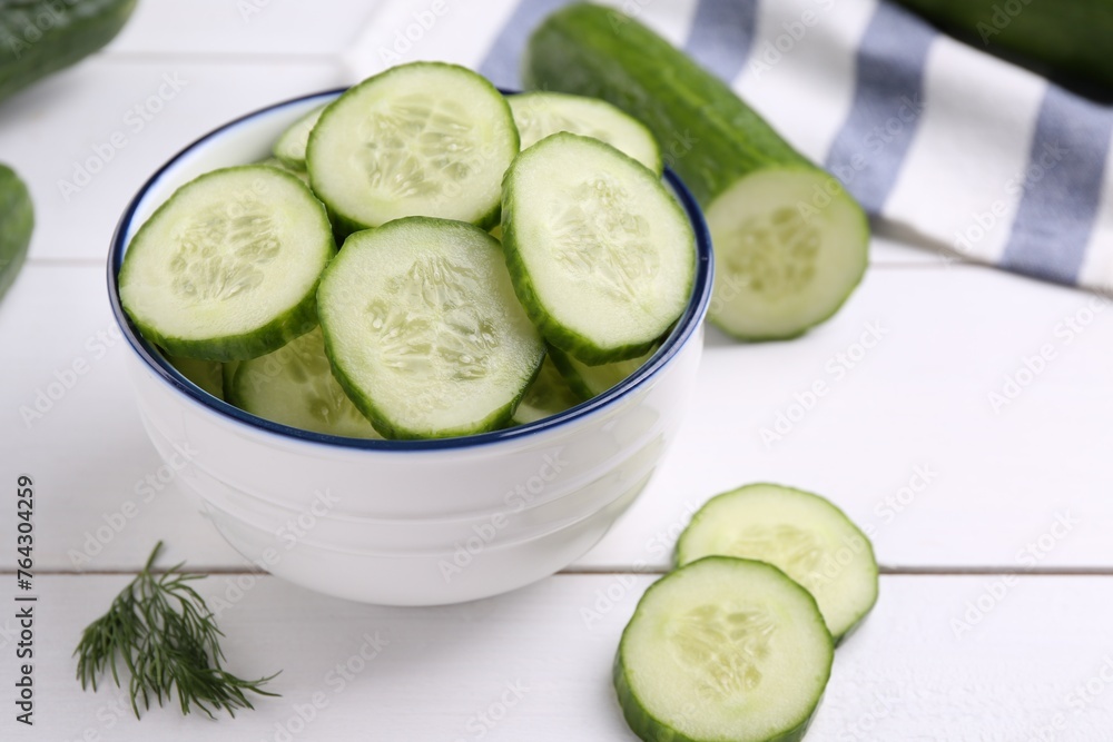 Cut cucumber in bowl, fresh vegetable and dill on white wooden table, closeup Cut cucumber in bowl, fresh vegetable and dill on white wooden table, closeup