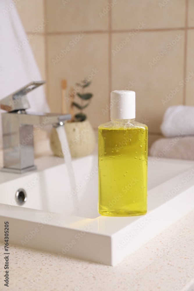 Fresh mouthwash in bottle with water drops on sink in bathroom Fresh mouthwash in bottle with water drops on sink in bathroom