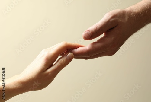 Man and woman holding hands together on beige background, closeup