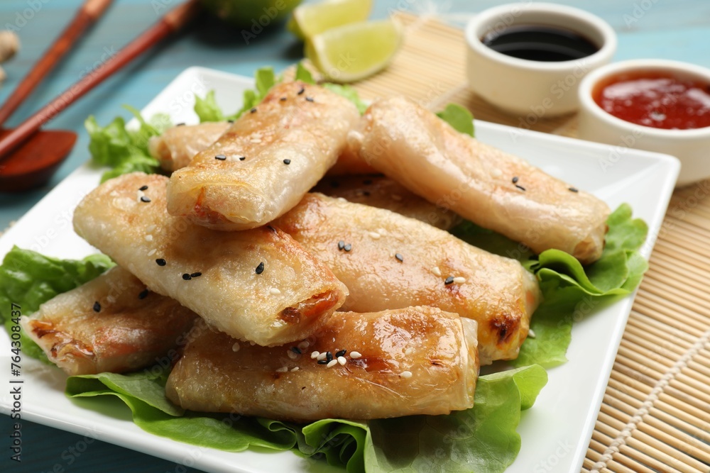 Tasty fried spring rolls and lettuce on light blue wooden table, closeup Tasty fried spring rolls and lettuce on light blue wooden table, closeup