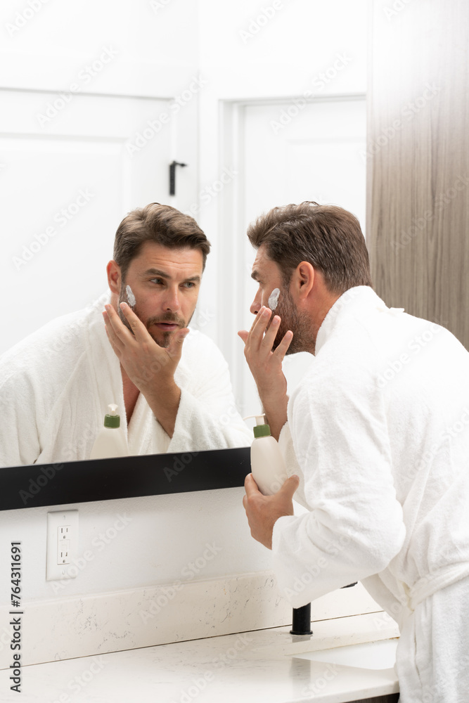 Beauty, skincare and man with cream on face using skincare products, lotion. Closeup of male face. Men's beauty. man is applying moisturizing and anti aging cream on his face against white background. Beauty, skincare and man with cream on face using skincare products, lotion. Closeup of male face. Men's beauty. man is applying moisturizing and anti aging cream on his face against white background.