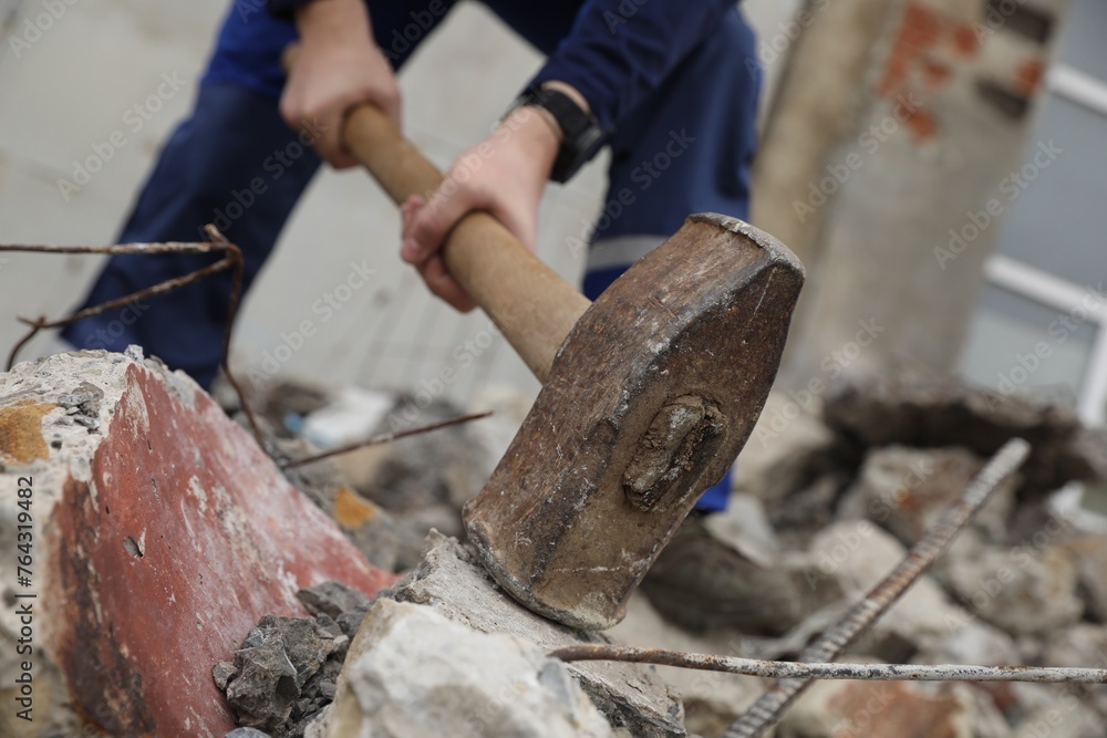 Man breaking stones with sledgehammer outdoors, selective focus