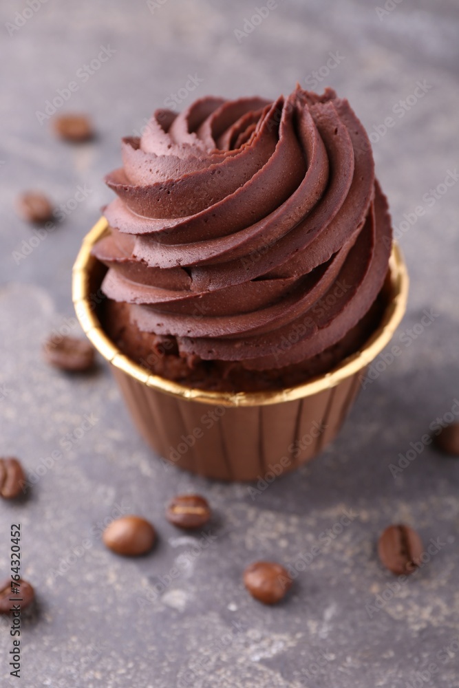 Delicious chocolate cupcake and coffee beans on grey textured table, closeup Delicious chocolate cupcake and coffee beans on grey textured table, closeup
