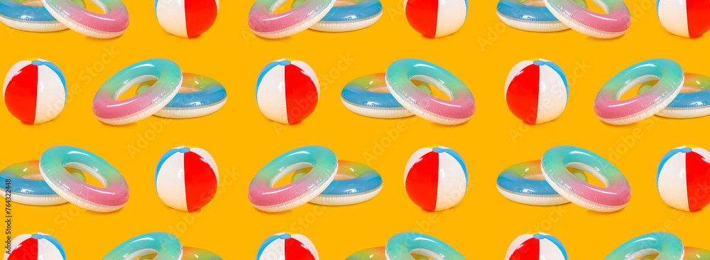 Many inflatable rings and beach balls on yellow background. Pattern for design