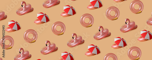 Many inflatable rings and umbrellas on beige background. Pattern for design