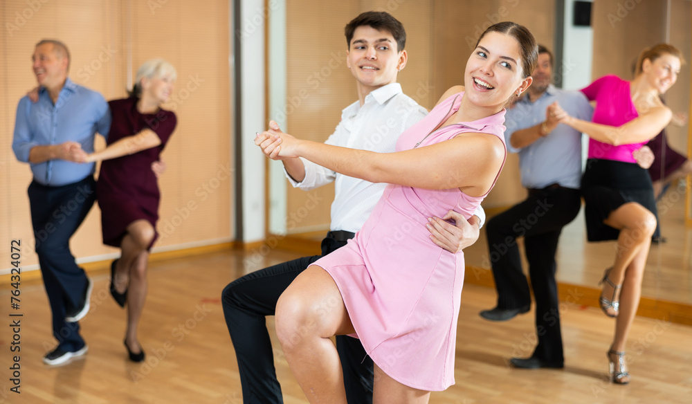 Obraz premium Active young pair practicing Latino dance in training hall during dancing-classes. Pairs training ballroom dance