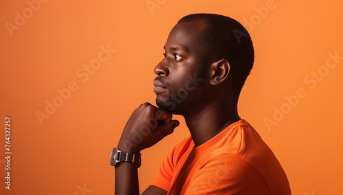 Close up portrait of black man thinking. Orange background. 