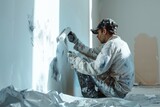 Painter with paint roller covering a wall in white paint, symbolizing renovation and the act of creation