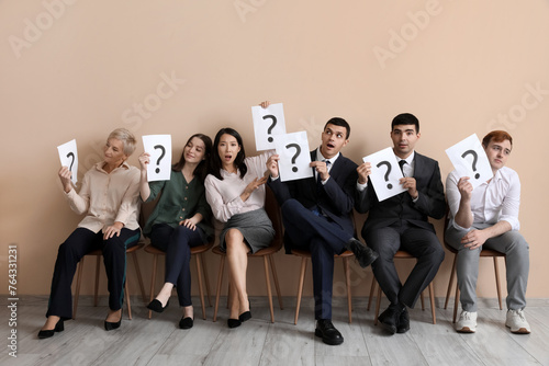 Applicants holding paper sheets with question marks near beige wall