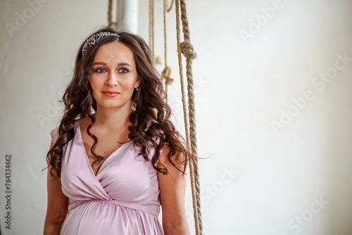 Portrait of a beautiful young pregnant woman in a pink dress.
