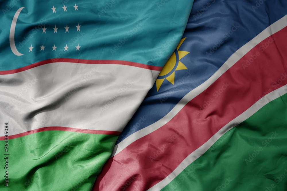 big waving national colorful flag of namibia and national flag of uzbekistan.