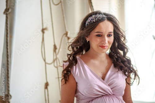 Portrait of a beautiful young pregnant woman in a pink dress.